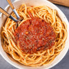 A bowl of spaghetti with marinara sauce and a wooden spoon.