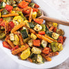 A white plate filled with roasted vegetables, including carrots, zucchini, bell peppers, and squash.