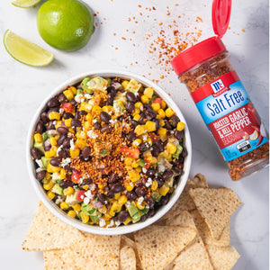 A bowl of black bean and corn salsa with McCormick Salt Free Roasted Garlic &amp; Bell Pepper Seasoning and tortilla chips.