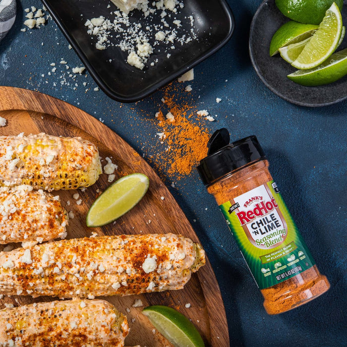 A plate of grilled corn on the cob topped with cheese and Franks RedHot Chile N Lime Seasoning Blend.