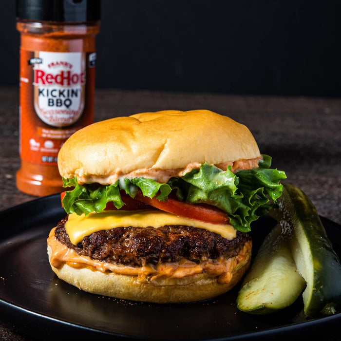 A RedHot Kickin BBQ burger with lettuce, tomato, cheese, and pickles on a black plate.