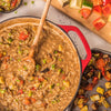 A pot of rice with vegetables and a wooden spoon.