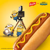 In a promotional advertisement for French'S Minion Yellow Mustard, 8 Oz, three Minions are on a film set, shooting a close-up of a hot dog topped with the bright yellow mustard.