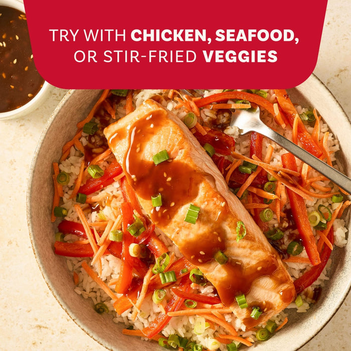 A piece of salmon drizzled with a savory sauce made from the Mccormick Sesame Ginger All Purpose Sauce Mix Envelope 1 Oz is served over a bed of rice and fresh vegetables.