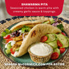 A serving suggestion for the Mccormick Regular Sauce And Seasoning Mix Envelope 1.37 Oz shows two delicious chicken shawarma pitas filled with fresh vegetables and a creamy garlic sauce.