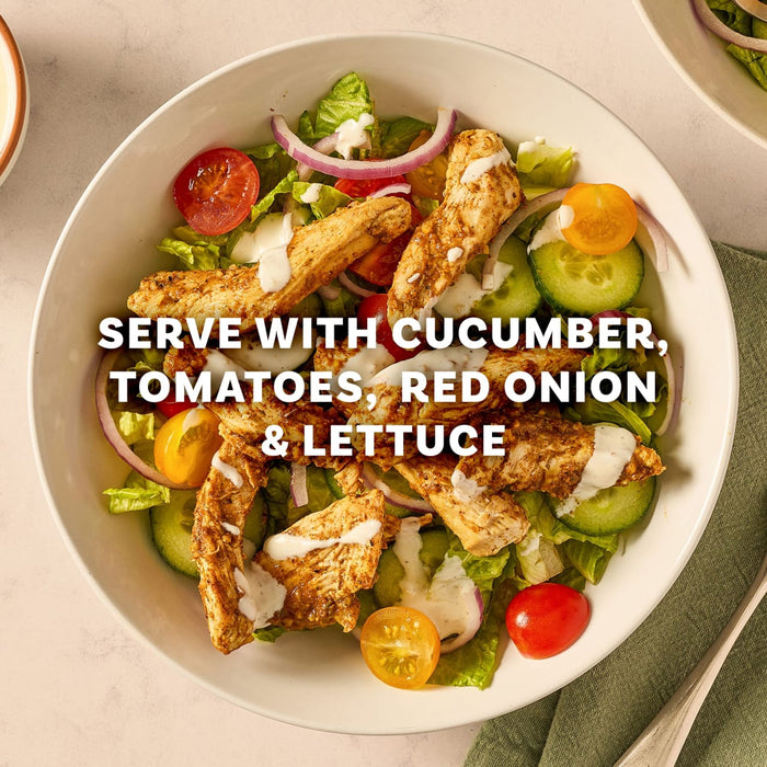 Seasoned chicken strips made with Mccormick Regular Sauce And Seasoning Mix Envelope 1.37 Oz are served over a fresh salad of lettuce, tomatoes, cucumber, and red onion in a white bowl.