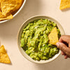 A delicious bowl of fresh guacamole, made with Mccormick Regular Seasoning Mix 1 Oz, is being enjoyed with tortilla chips.