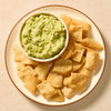 A fresh bowl of guacamole, prepared using Mccormick Regular Seasoning Mix 1 Oz, is presented on a plate with a side of crackers for dipping.