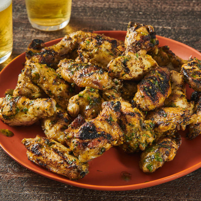 A plate of grilled chicken wings with a side of beer.