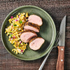 A plate of grilled pork tenderloin with a side of corn salad.