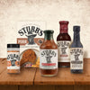 A selection of Stubb's BBQ sauces and seasonings are displayed on a wooden table.