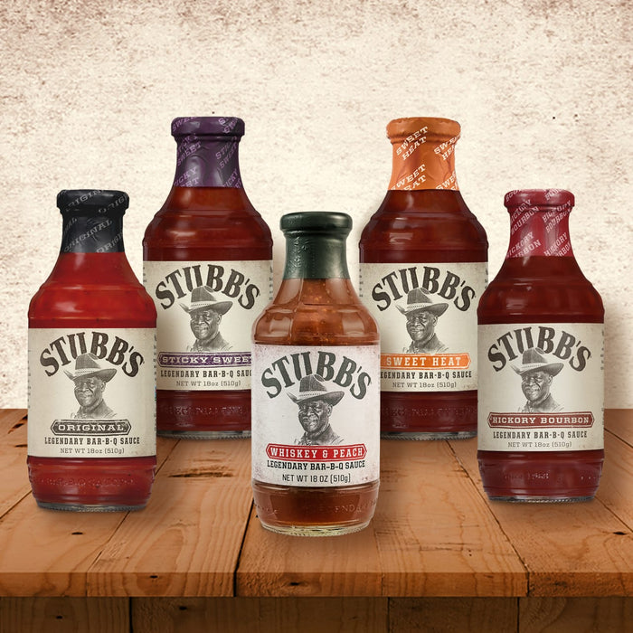 A selection of Stubb's BBQ sauces in various flavors are displayed on a wooden surface.