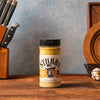 A container of Stubb's Chicken Rub seasoning sits on a wooden surface.