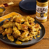 A plate of chicken wings glazed with Stubb's brand BBQ sauce is displayed next to a bottle of the sauce.