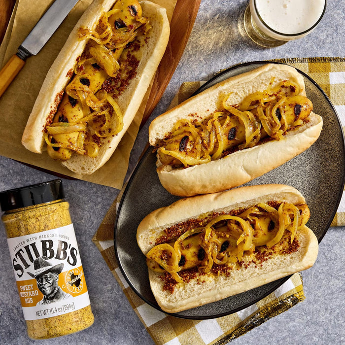 Three hot dogs topped with grilled onions and Stubb's Beef Spice Rub are displayed on a plate and wooden board.