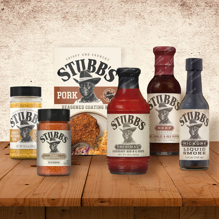 A collection of Stubb's products including Stubbs Smkhouse E seasoning alongside Sweet Mustard Rub, Pork Seasoned Coating Mix, Original Bar-B-Q Sauce, Beef Marinade, and Hickory Liquid Smoke on a wooden surface.