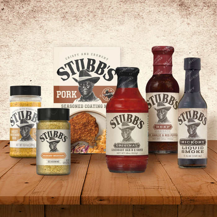A collection of Stubb's products including Stubbs Hkry Must E seasoning and Original Bar-B-Q Sauce are displayed on a rustic wooden table.