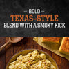 A bowl of creamy potato salad seasoned with Stubbs Hkry Must E is served alongside pieces of cornbread on a rustic wooden table, highlighting a bold Texas-style blend with a smoky kick.