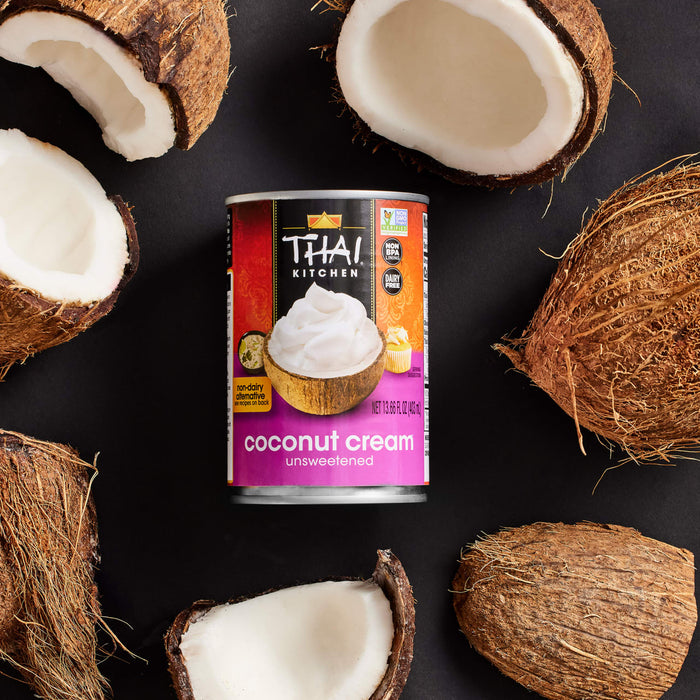 A can of Thai Kitchen Coconut Cream, unsweetened, surrounded by coconut halves.