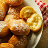 A plate of freshly made donuts covered in powdered sugar.