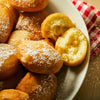 A plate of freshly made donuts covered in powdered sugar.