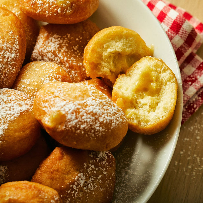 A plate of freshly made donuts covered in powdered sugar.
