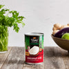 A can of Thai Kitchen Organic Coconut Milk sits on a wooden surface, surrounded by fresh ingredients like ginger and eggplant.