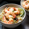 A bowl of shrimp with rice and a lime wedge.