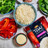 A bowl of cooked Thai Kitchen jasmine rice with red bell peppers, broccoli, snow peas, and sesame seeds.