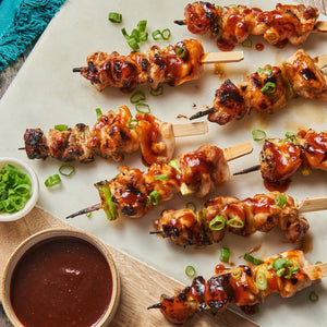Chicken skewers with a sweet and savory glaze, garnished with green onions.