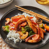 A plate of chicken stir fry with vegetables and rice.
