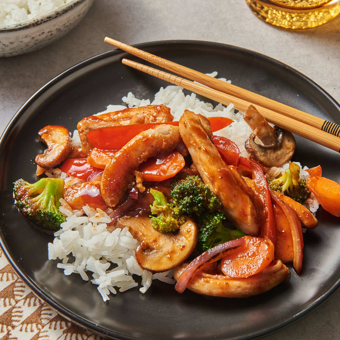 A plate of chicken stir fry with vegetables and rice.