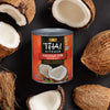 A can of Thai Kitchen coconut milk is surrounded by fresh coconuts.