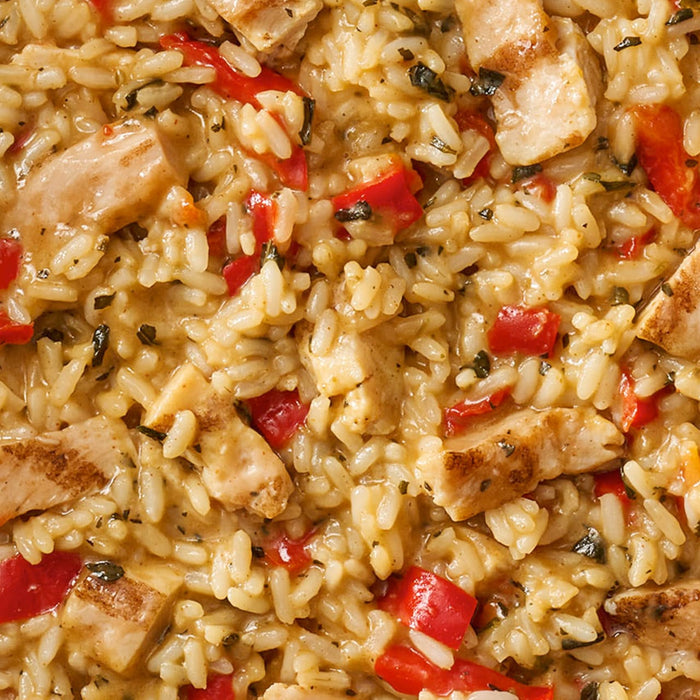 A close-up of a prepared meal of chicken and rice with red peppers, made with a package of Thai Kitchen, 9.0 Oz.