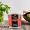 A container of Thai Kitchen Red Curry Paste sits on a wooden surface, suggesting its use in preparing authentic Thai cuisine.