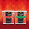 Two containers of Thai Kitchen red and green curry paste are displayed against a red background.