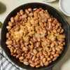 A skillet filled with cooked pinto beans and onions, likely part of a Southwestern or Tex-Mex meal.