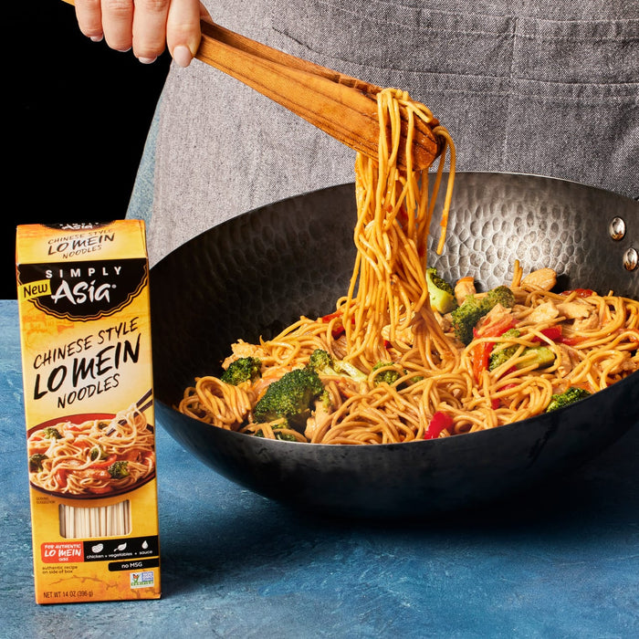 A hand uses tongs to toss Simply Asia Chinese Style Lo Mein noodles in a wok.