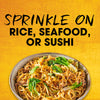 The image promotes sprinkling a seasoning on rice, seafood, or sushi, showcasing a bowl of noodles with vegetables.