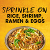 A bowl of ramen with the text Sprinkle on rice, shrimp, ramen &amp; eggs.