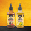 Two bottles of Sauce Shop hot sauce, one Black Garlic and one Yuzu Kosho, stand side-by-side against a textured background.