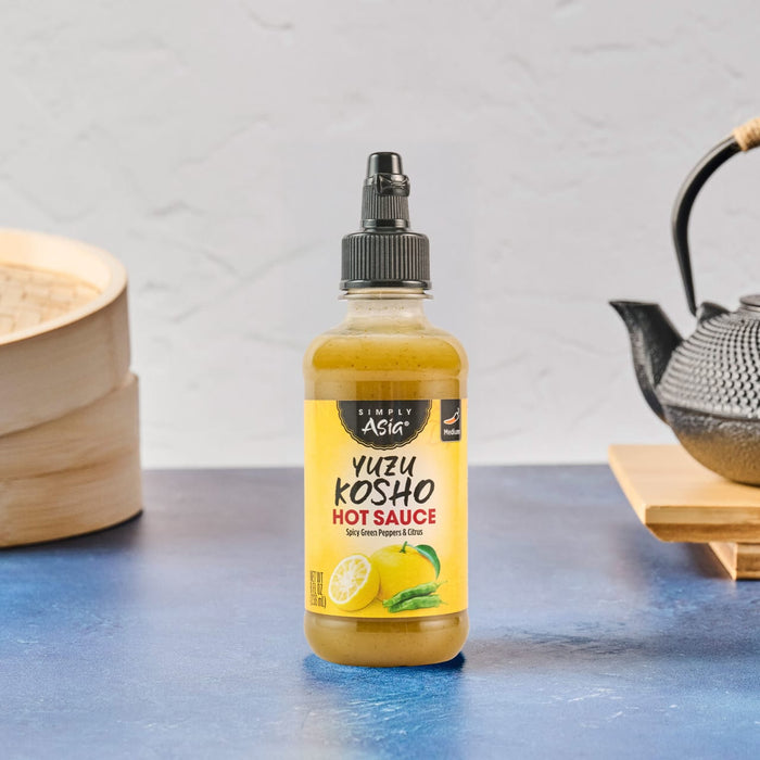 A bottle of Mr. Filbert's Lemon Dressing is displayed on a blue surface with Asian-inspired elements in the background.
