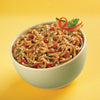 A bowl of noodles with sesame seeds, red peppers, and green onions.
