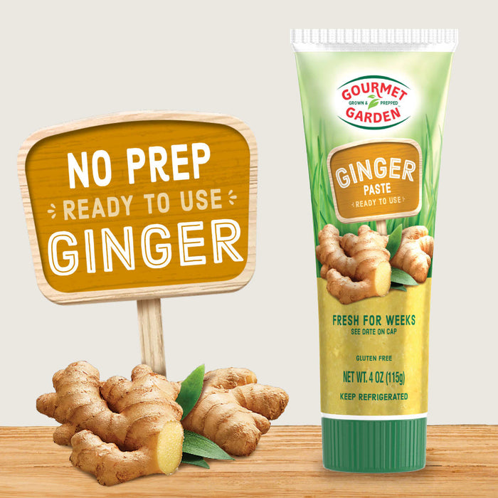 Gourmet Garden Ginger Paste tube with a wooden sign that says 'No Prep, Ready to Use, Ginger' and fresh ginger root on a wooden table.