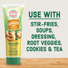 Gourmet Garden Ginger Paste tube with a wooden sign and ginger root on a wooden surface.