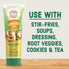 Gourmet Garden Ginger Paste tube with a wooden sign and ginger root on a wooden surface.