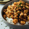 A bowl of rice topped with a savory meat dish and garnished with parsley.