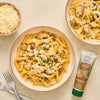 A plate of pasta with mushrooms and grated cheese, alongside a tube of Amore Mushroom Paste.