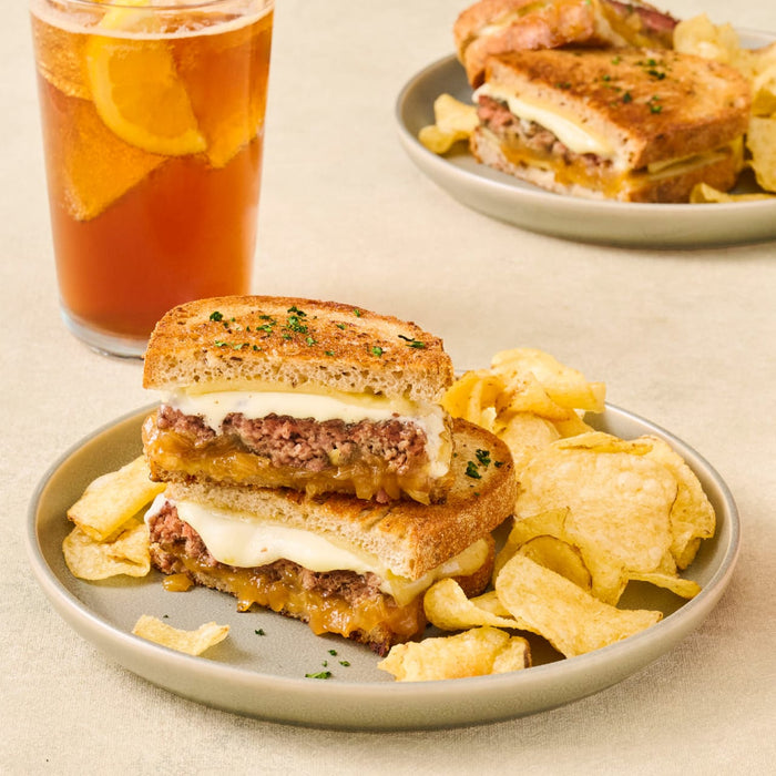 A delicious grilled cheese sandwich with chips and a refreshing drink is presented on a plate.