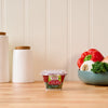 A container of Gourmet Garden Lightly Dried Italian Seasoning Blend sits on a wooden countertop.